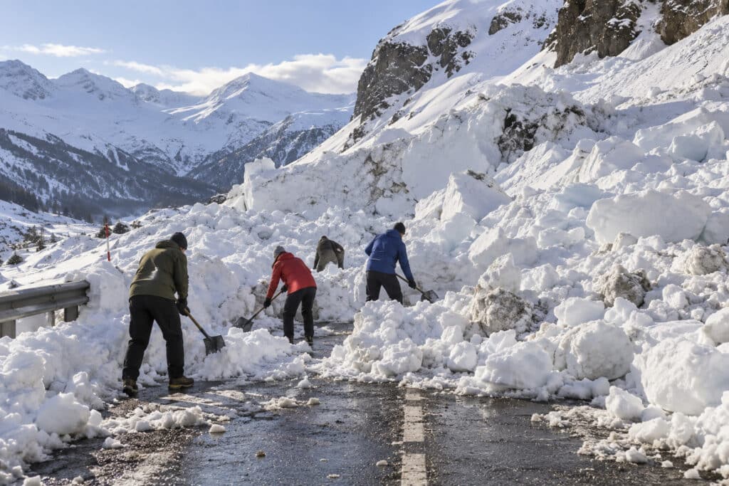 People clearing a path through an avalanche-blocked road, illustrating movement from understanding a problem towards resolution